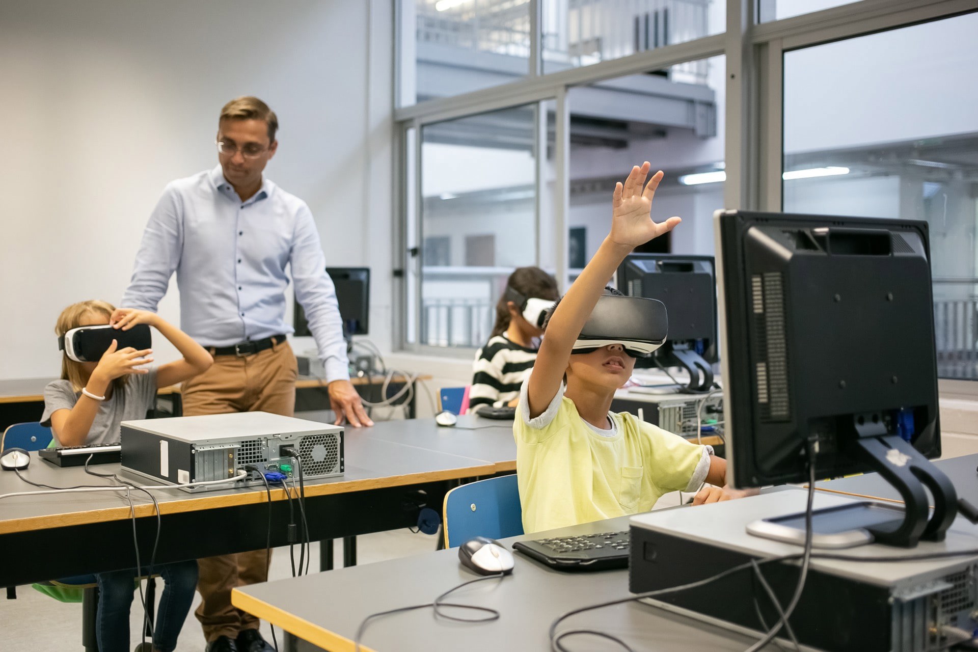 A teacher and three students using VR headsets in a classroom.